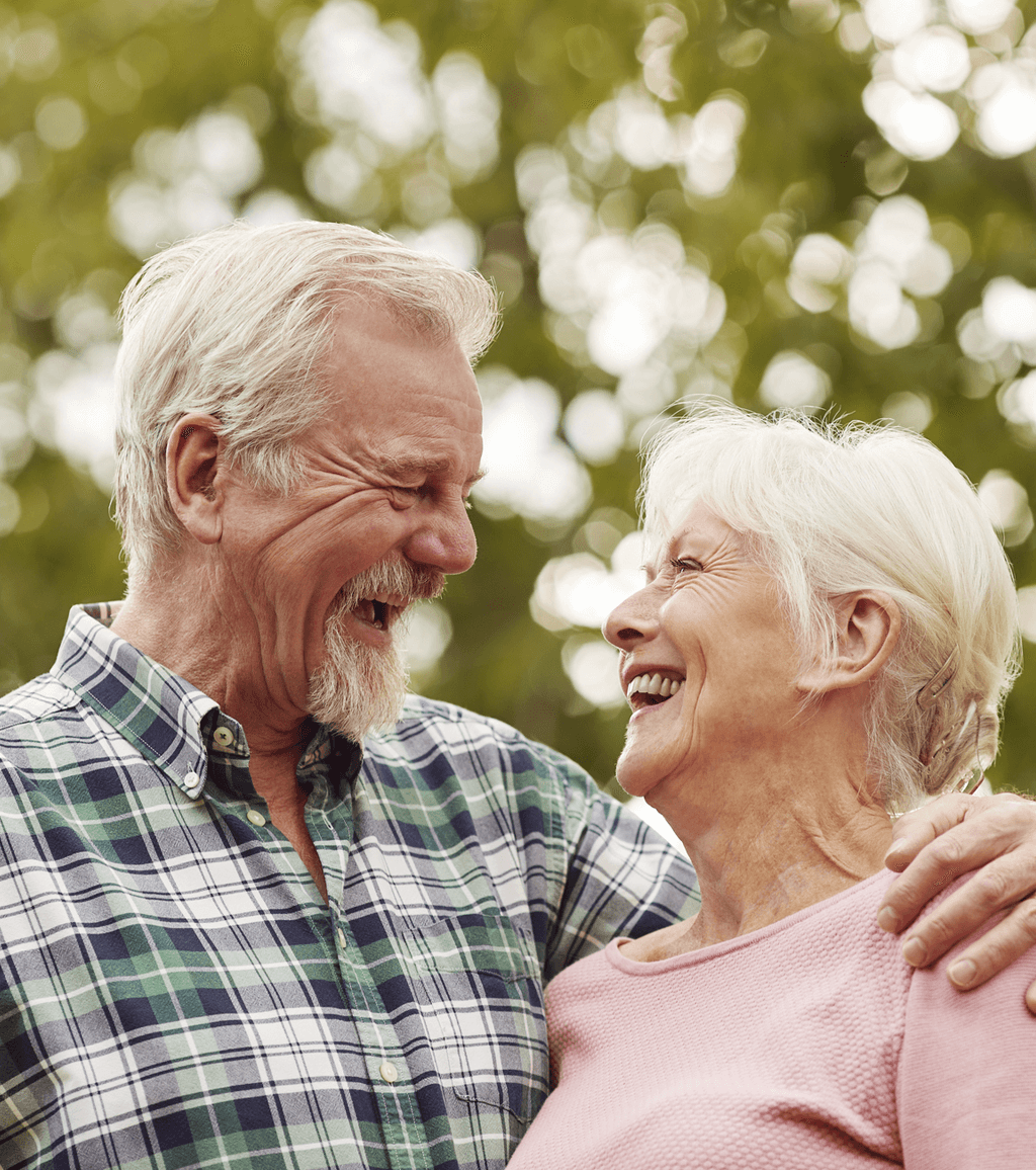 An elderly couple laughing together with thick silver hair