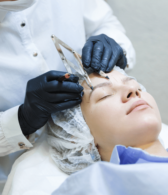 a surgeon marking a woman’s eyebrows for an eyebrow transplant