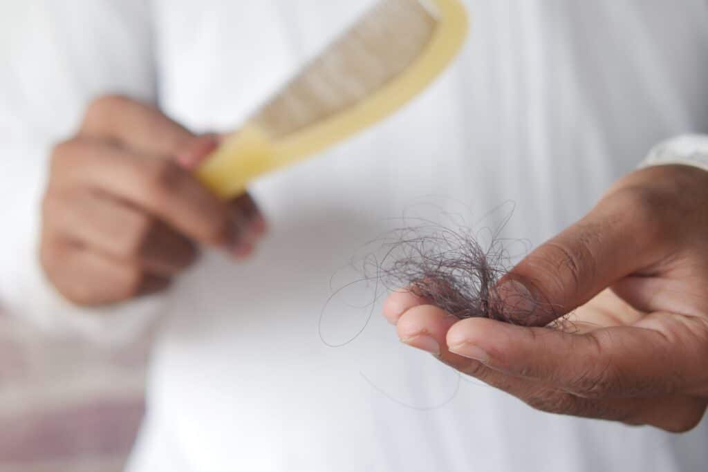 Person holding a clump of loose hair with a comb in the other hand