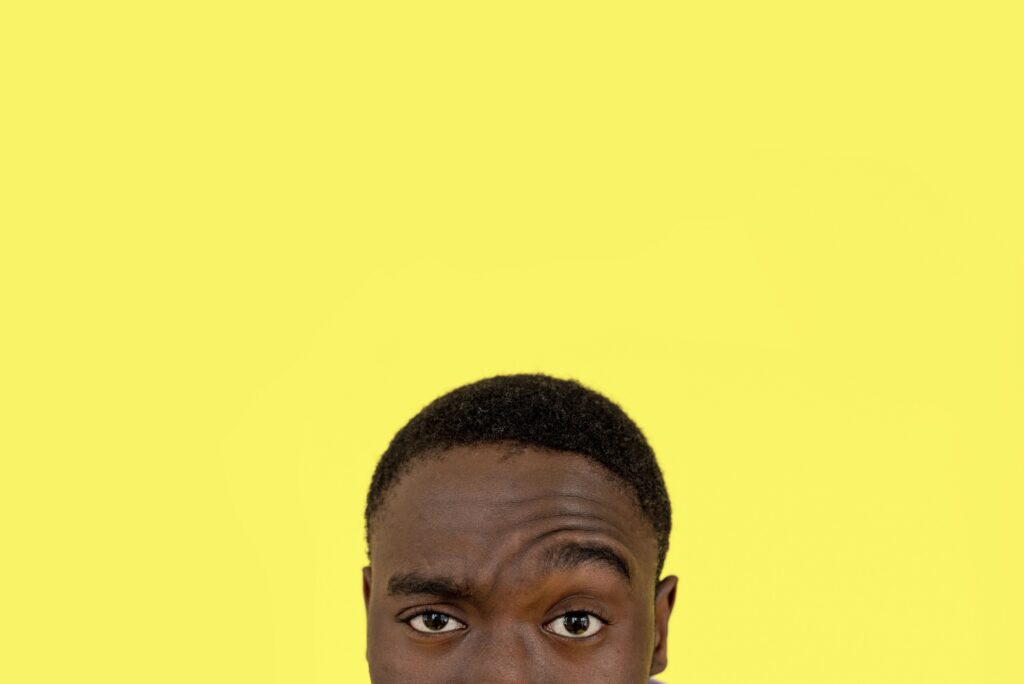 Man raising his eyebrow against a yellow background