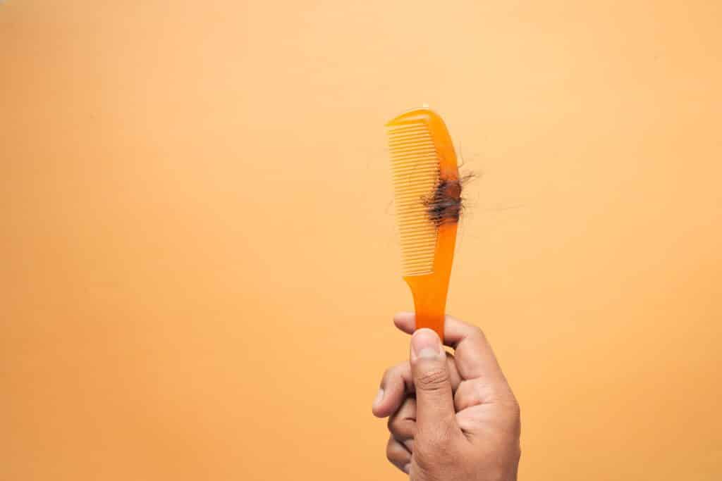 Orange comb with clump of hair