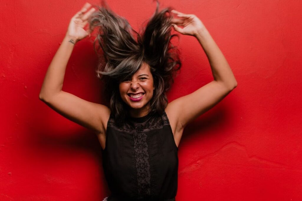 Smiling woman playing with hair against red wall