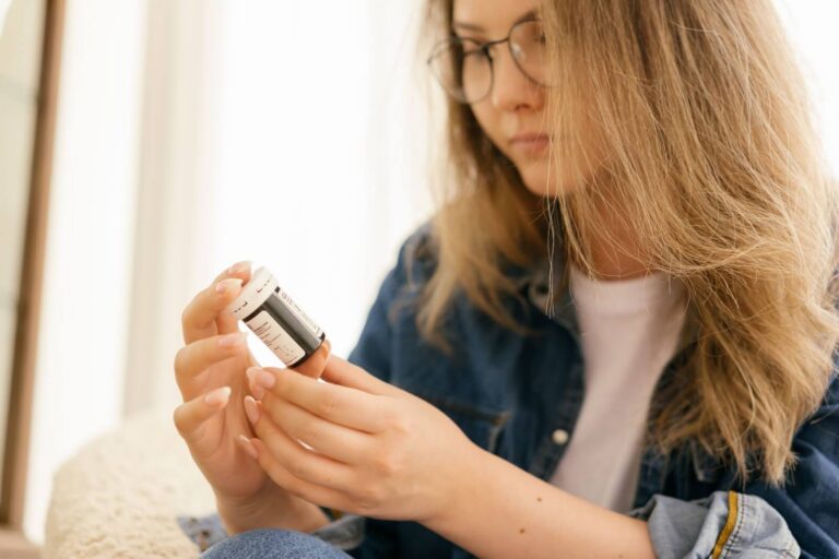 Woman with blonde hair reading a medicine bottle
